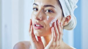 Femme appliquant une crème hydratante sur son visage pour prendre soin de sa peau grasse.